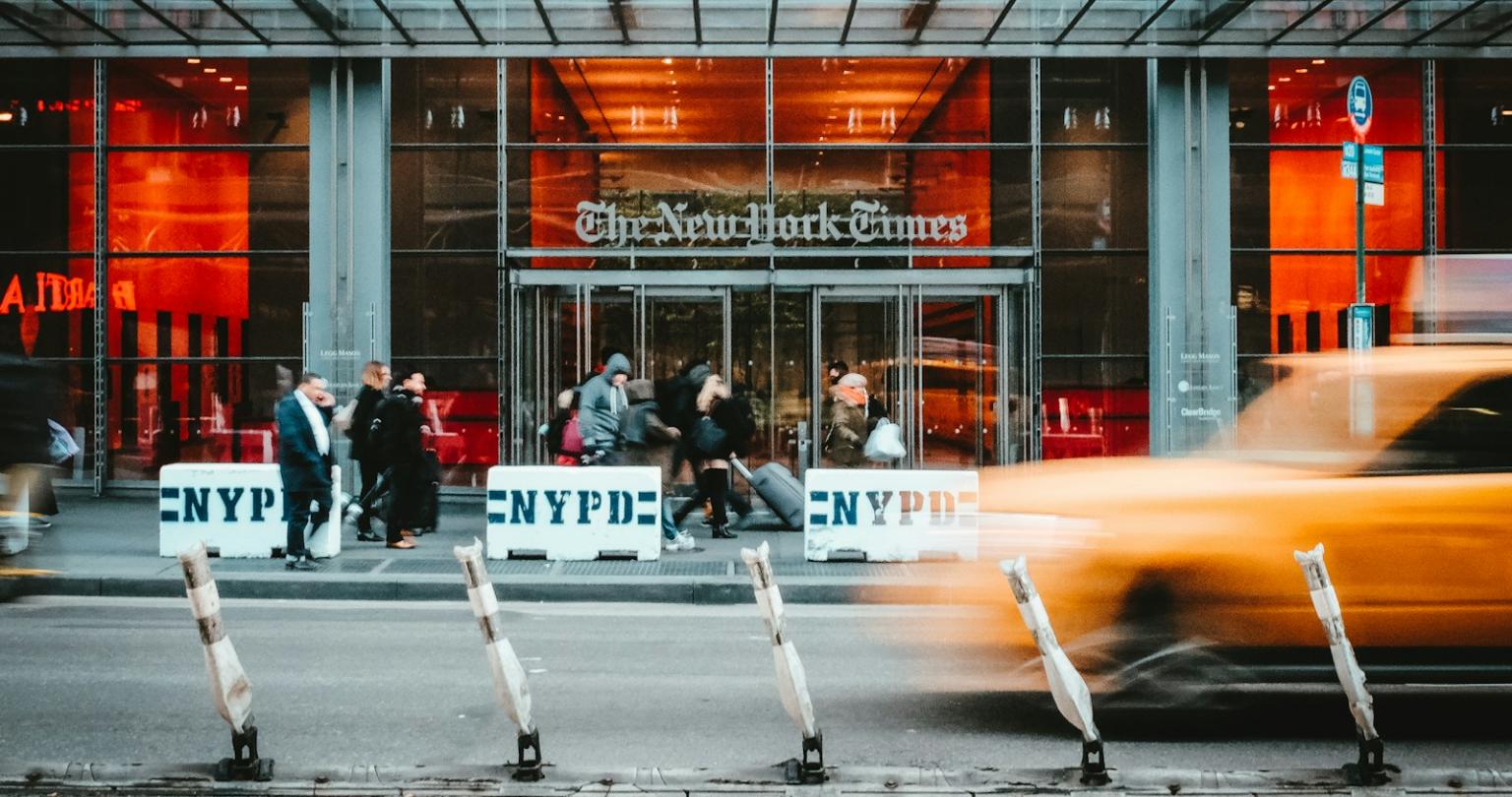 time lapse photo of yellow taxi driving past the NYT